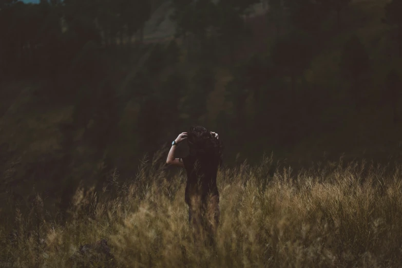 man standing in grassy field during sunset holding backpack