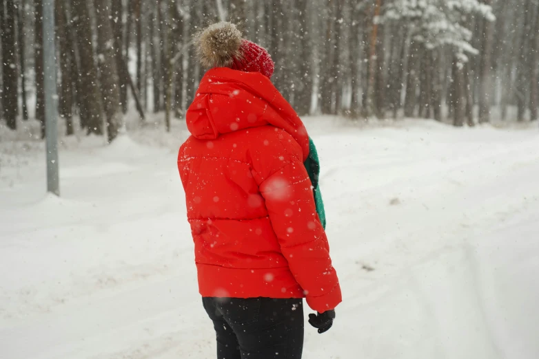 a man in red jacket walking through snowy woods