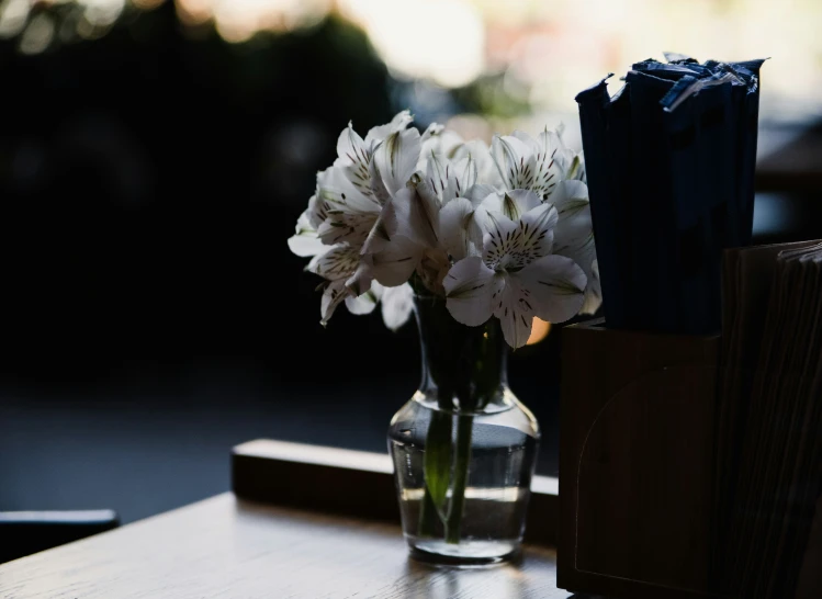 white flowers are in a clear vase on a table