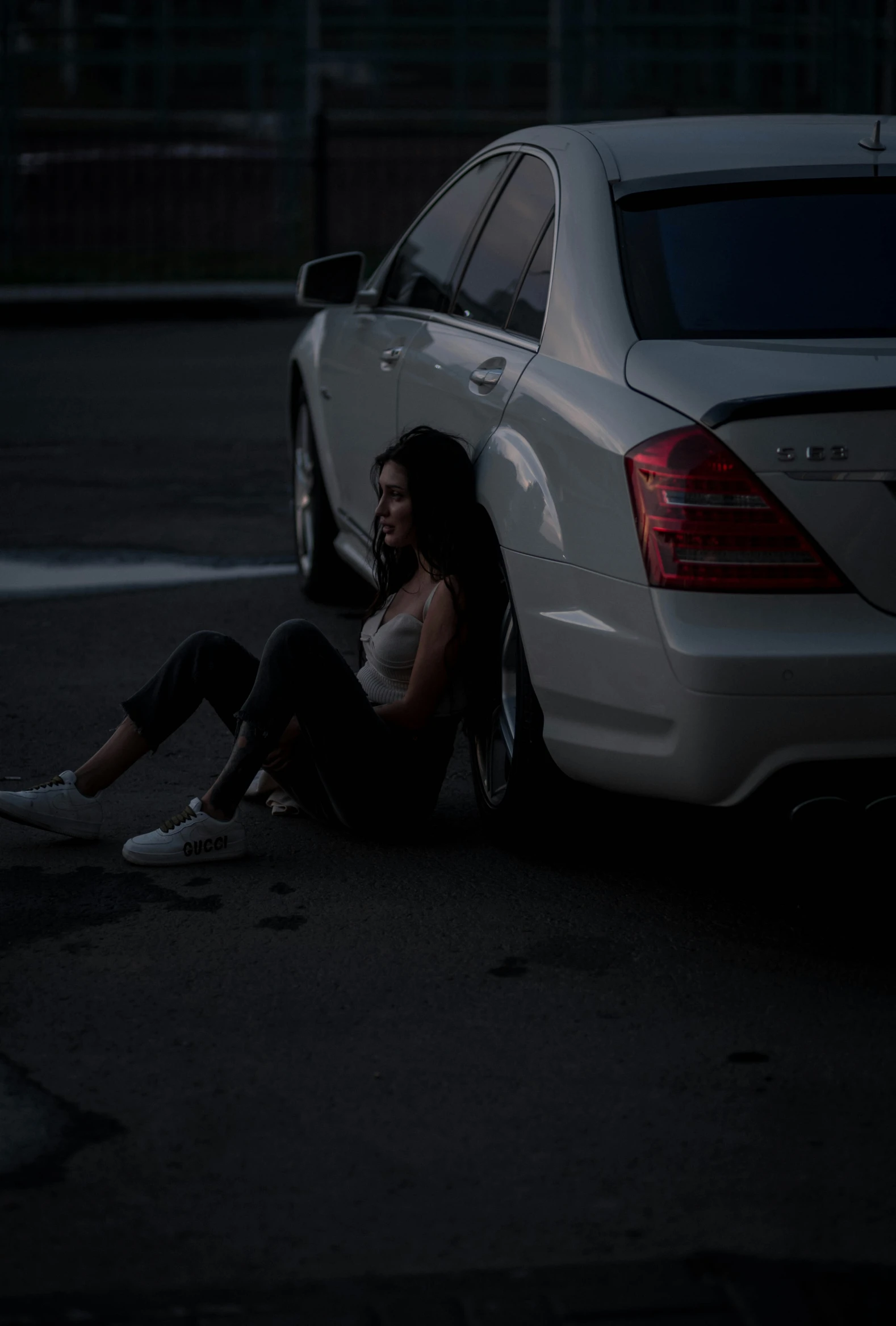 a woman sitting on the ground next to a car