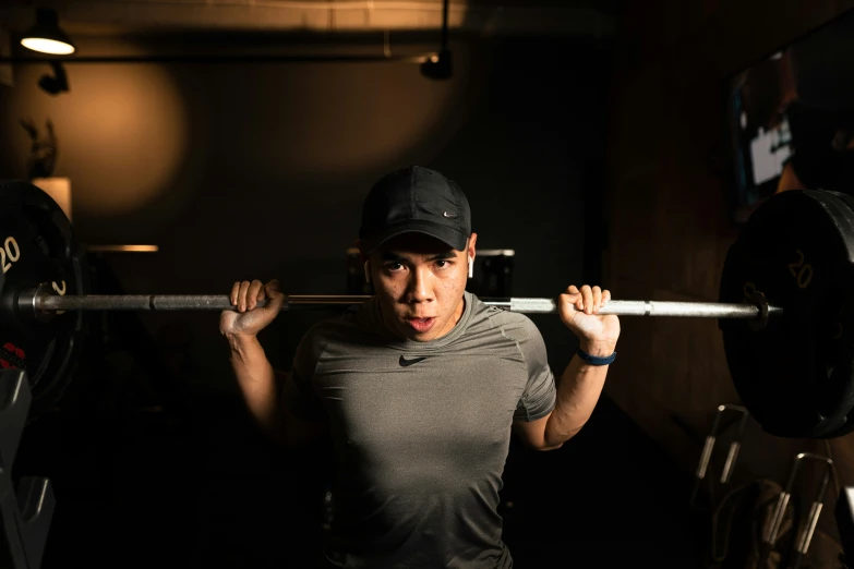 a woman with a black cap lifts a barbell