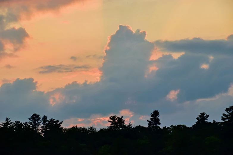 clouds are lit with the setting sun and green trees