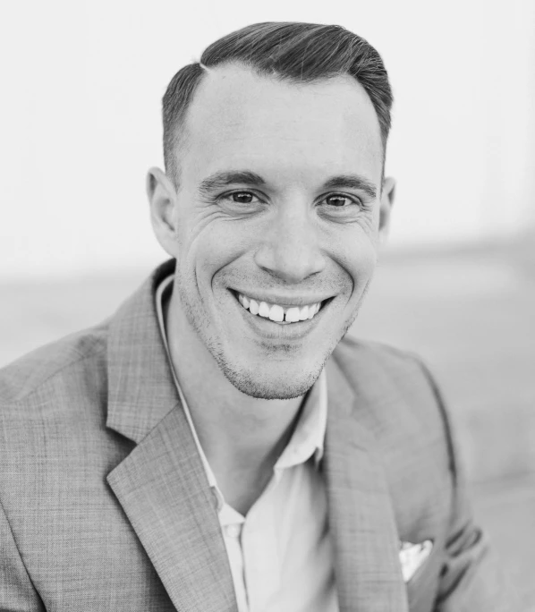 a man smiling in a suit and tie