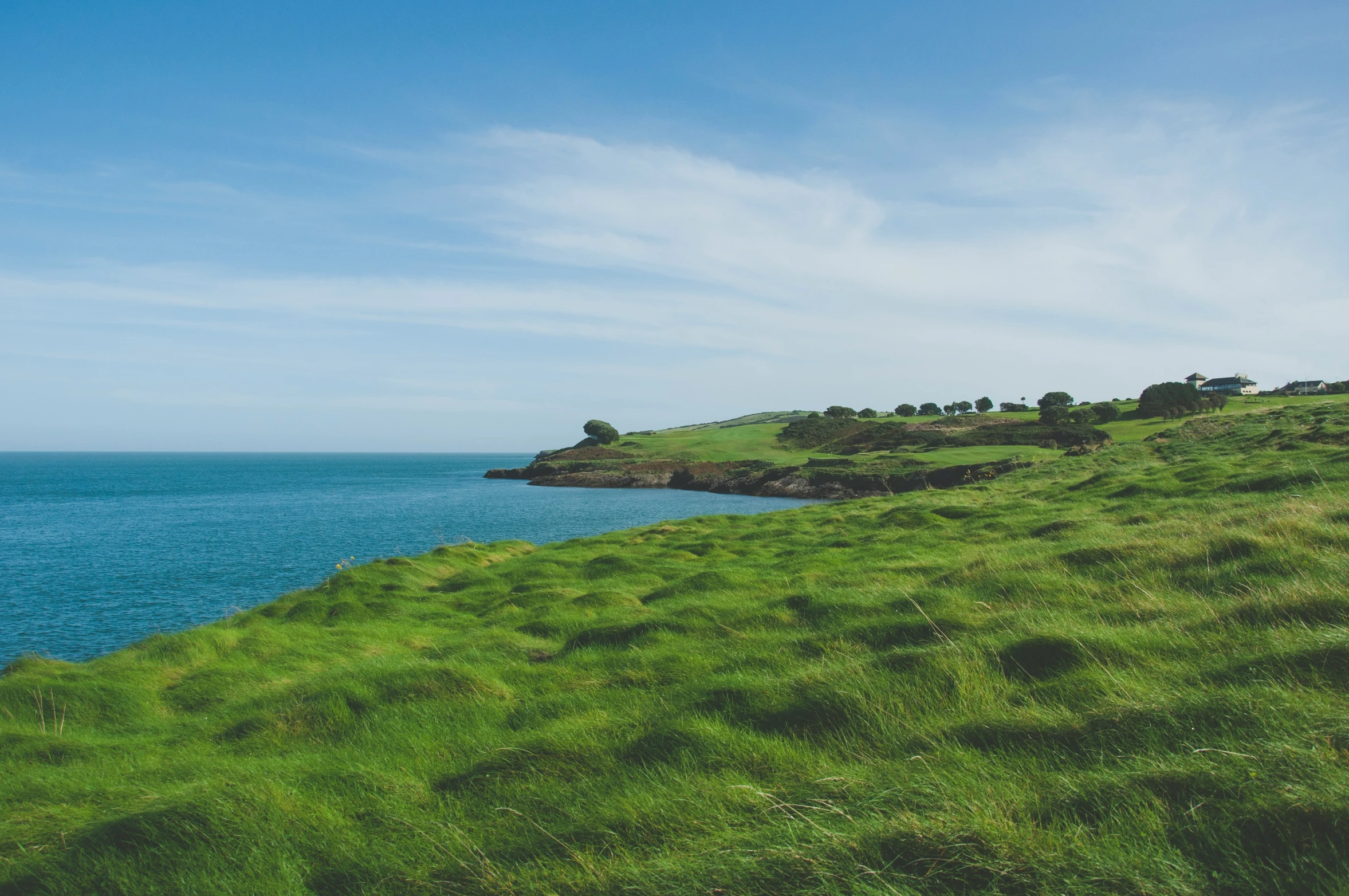 the green hills on the side of a grassy hill overlooking the ocean