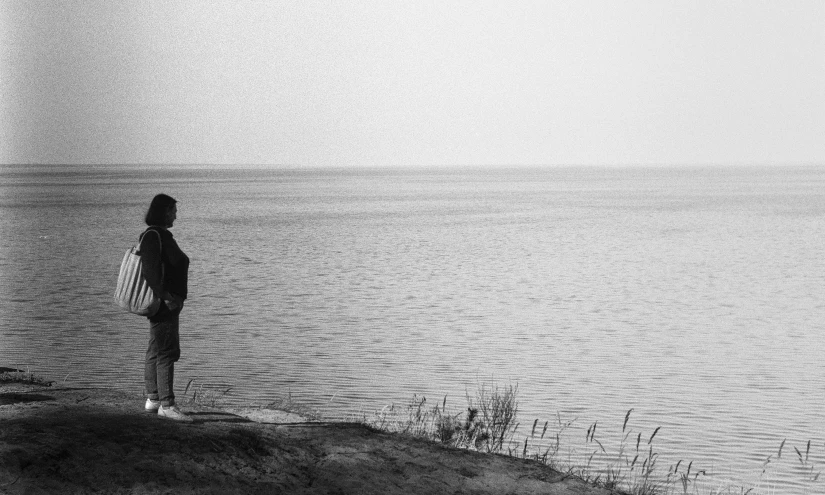 the person stands on the edge of a large body of water