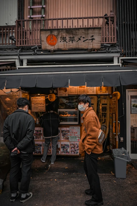 two people are standing outside of a shop while wearing masks