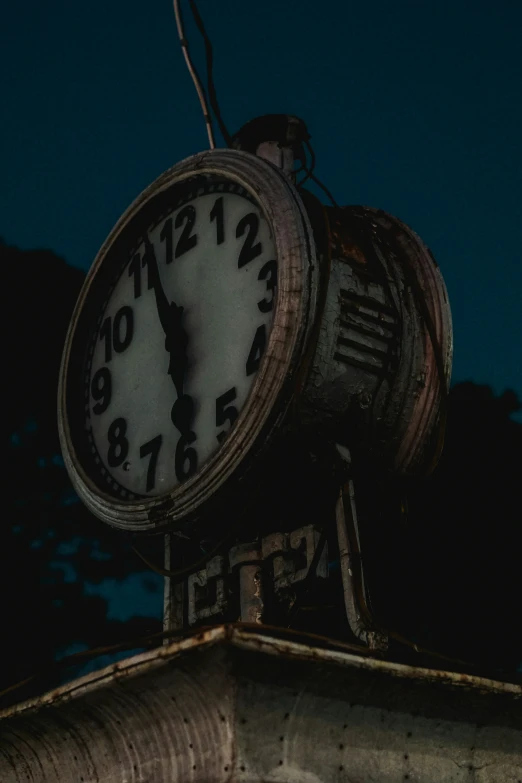 a large clock on top of a pole at night