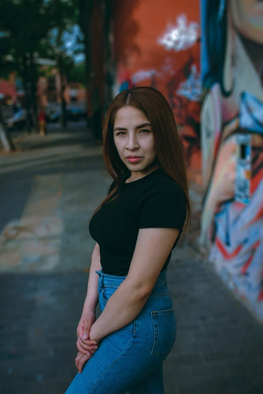 a woman poses in front of a colorful wall