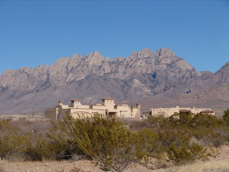 the mountains are in the background, with an adobe style house in front