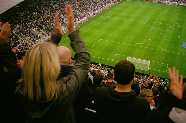 a crowd at a soccer game with the crowd holding their hands up in front of the camera
