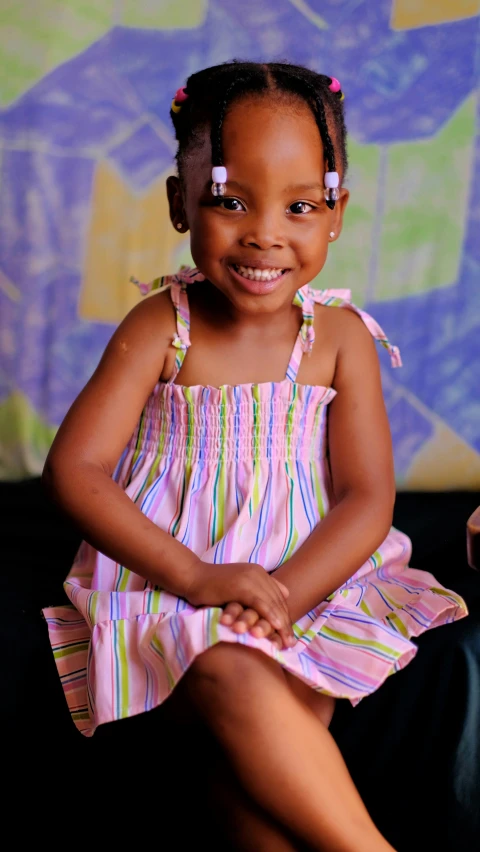 a young black girl in a pink dress sitting on the floor