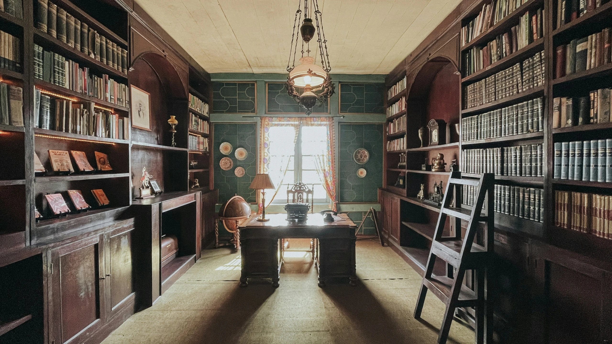 the room has many bookshelves and a ladder