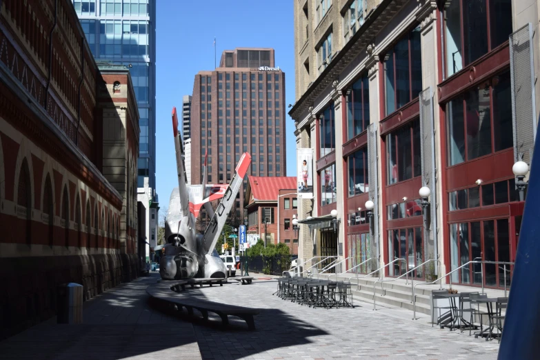 a street scene with a train sculpture and tall buildings