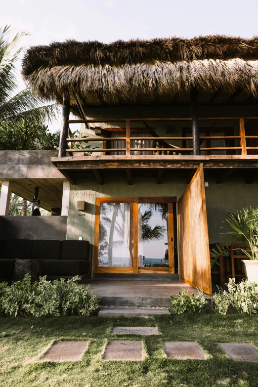 the entrance to a house with large straw roof