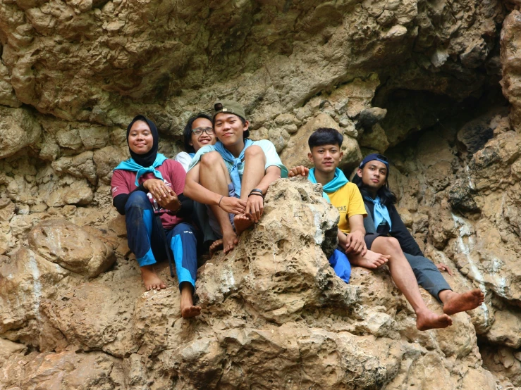 a group of people in colorful clothes sitting on a large rock