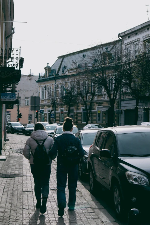 three people walking down a sidewalk in front of some buildings