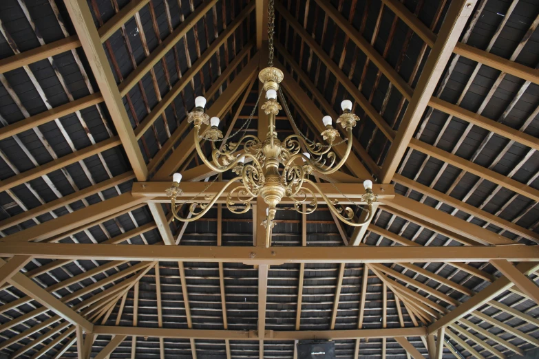 the inside of a barn with a chandelier and wood roof