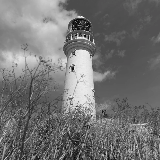 a tall white light house sitting on top of a lush green field