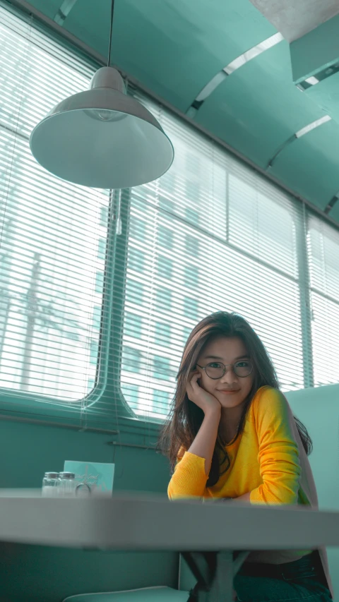 a smiling woman in glasses is leaning on the table