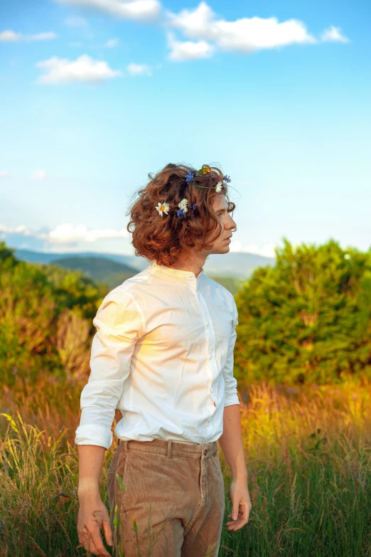 a young man with long hair and a shirt on standing in tall grass