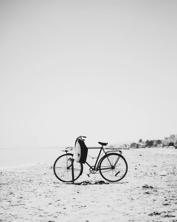 man with a bicycle standing on the beach by the water