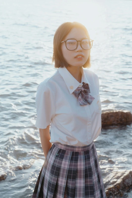 a girl is standing on the shore near the ocean