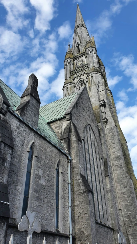an old gray church with many steeples against a blue sky with clouds