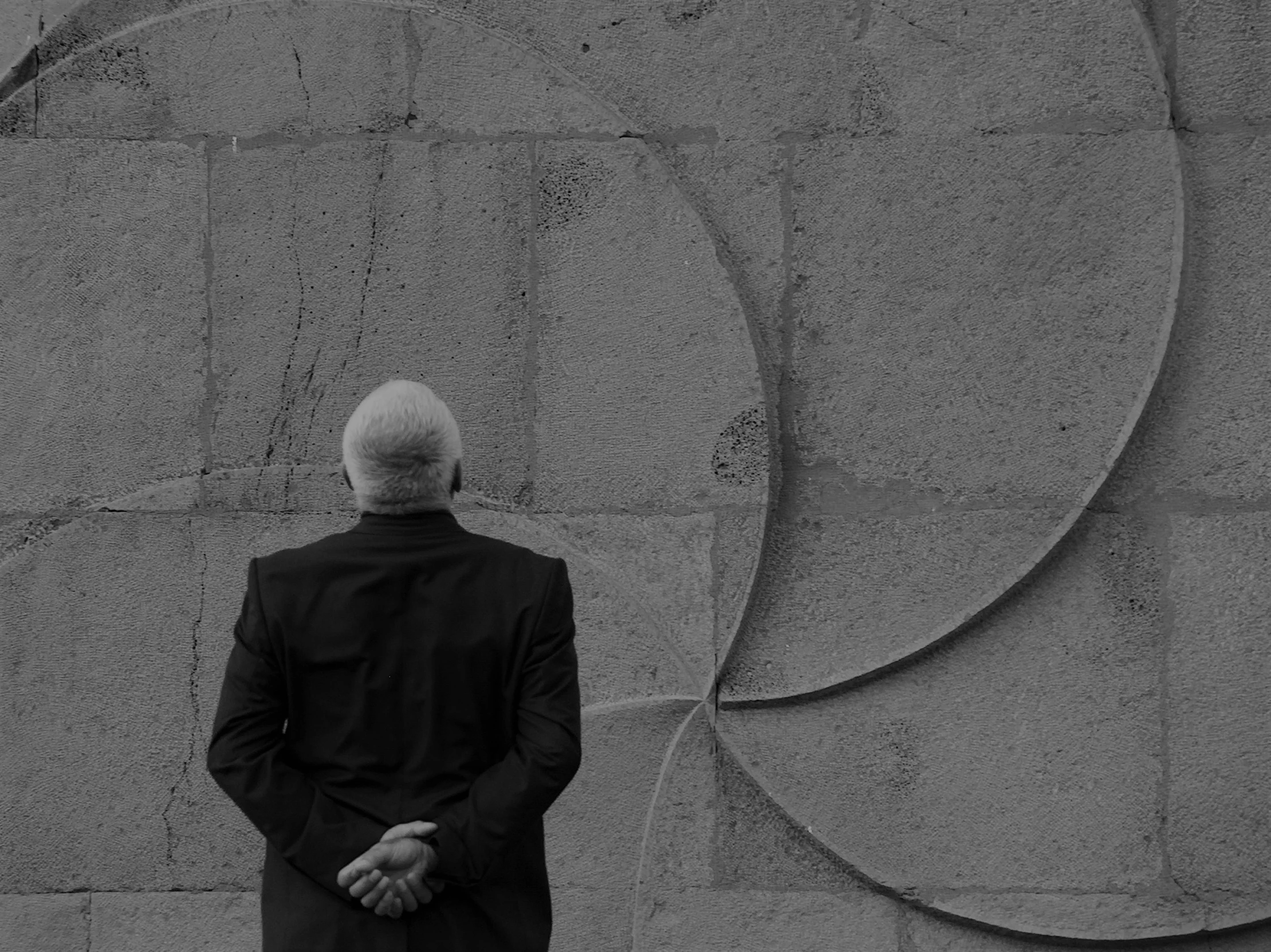 black and white po of man in front of a concrete wall