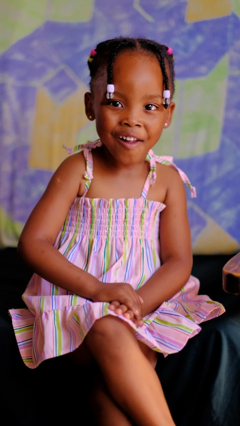 a little girl smiling in front of a floral wall