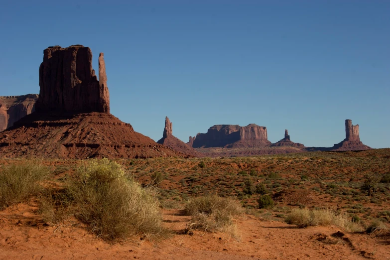 a large mountain covered in desert vegetation under a blue sky