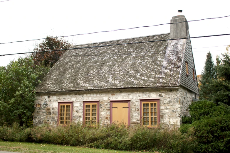 a building made of stone surrounded by shrubbery and power lines