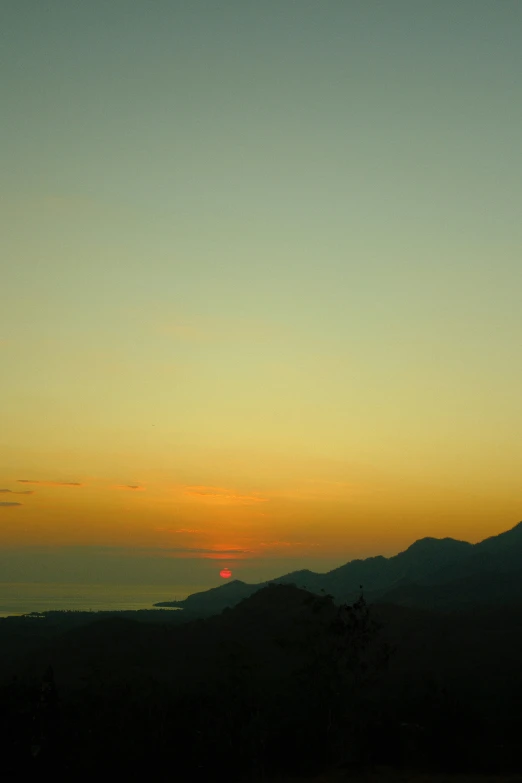 a sky view of mountains with the sun setting