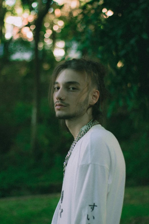 a man wearing a cross necklace in the woods