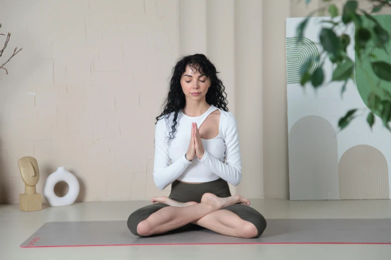 a woman in a white shirt and brown pants doing yoga