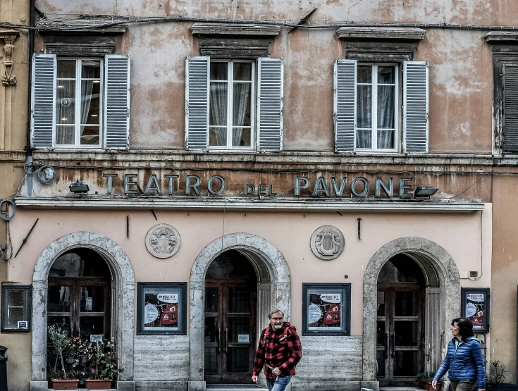 an old building with people walking by on the street