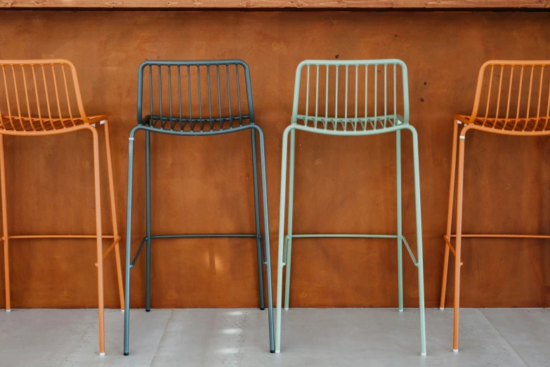some metal chairs next to an orange wall