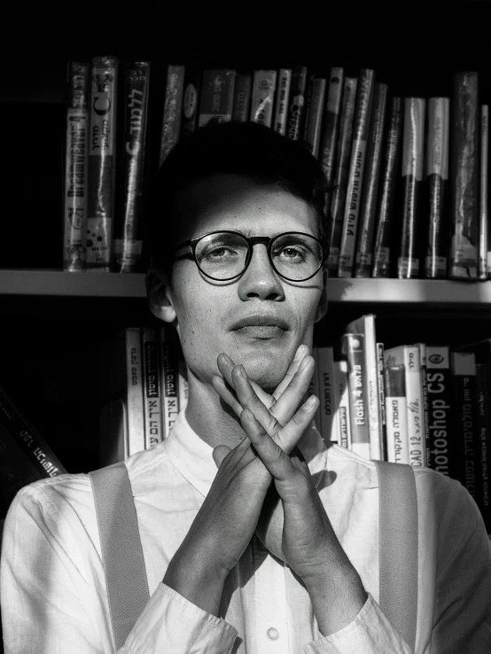 a man in suspenders is posing for a po by a book shelf