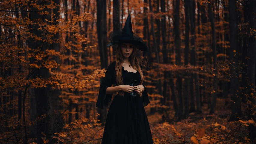 a young woman dressed up in black standing next to trees