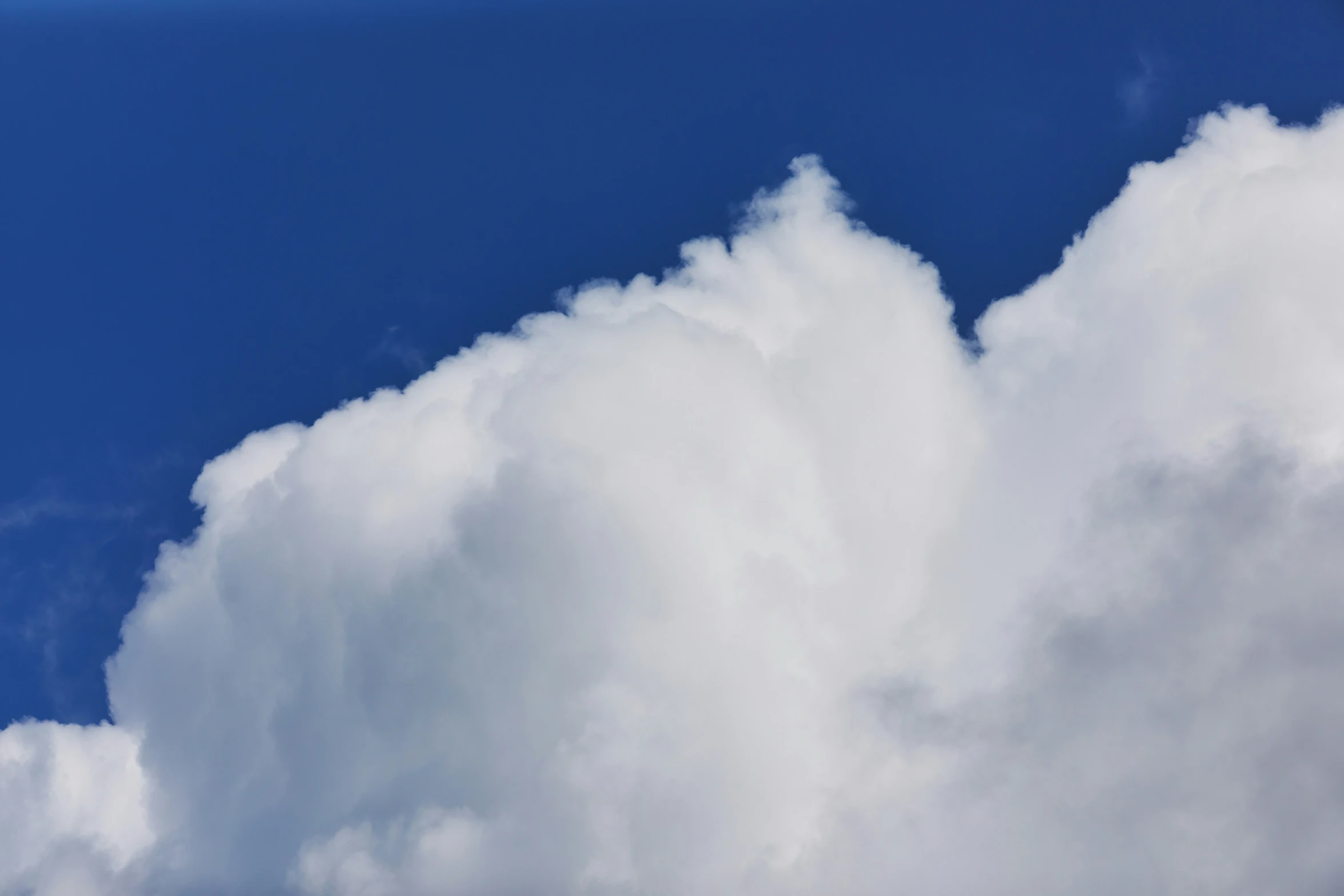 an airplane flies through the clouds in a blue sky