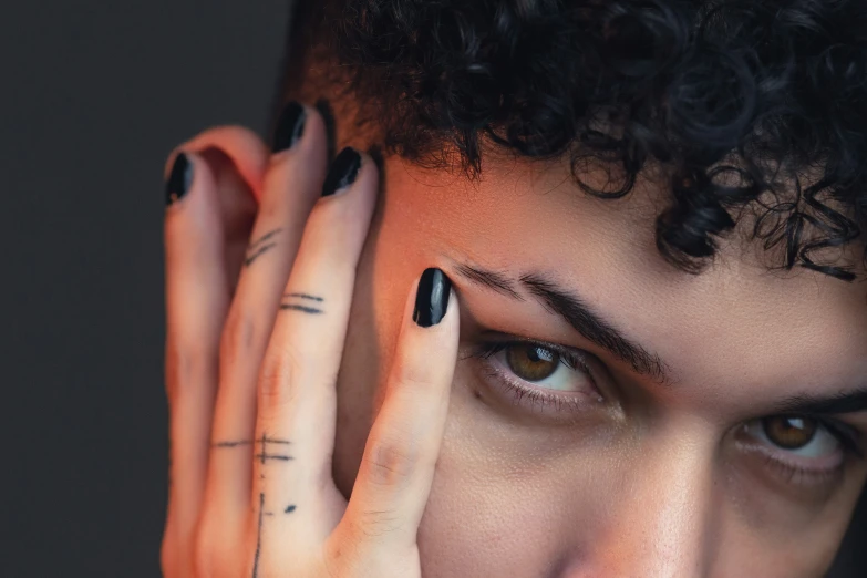 a woman with dark hair and white makeup has black nails