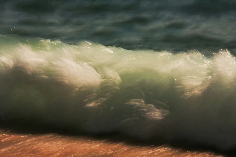 a wave breaking behind a rocky beach next to the ocean