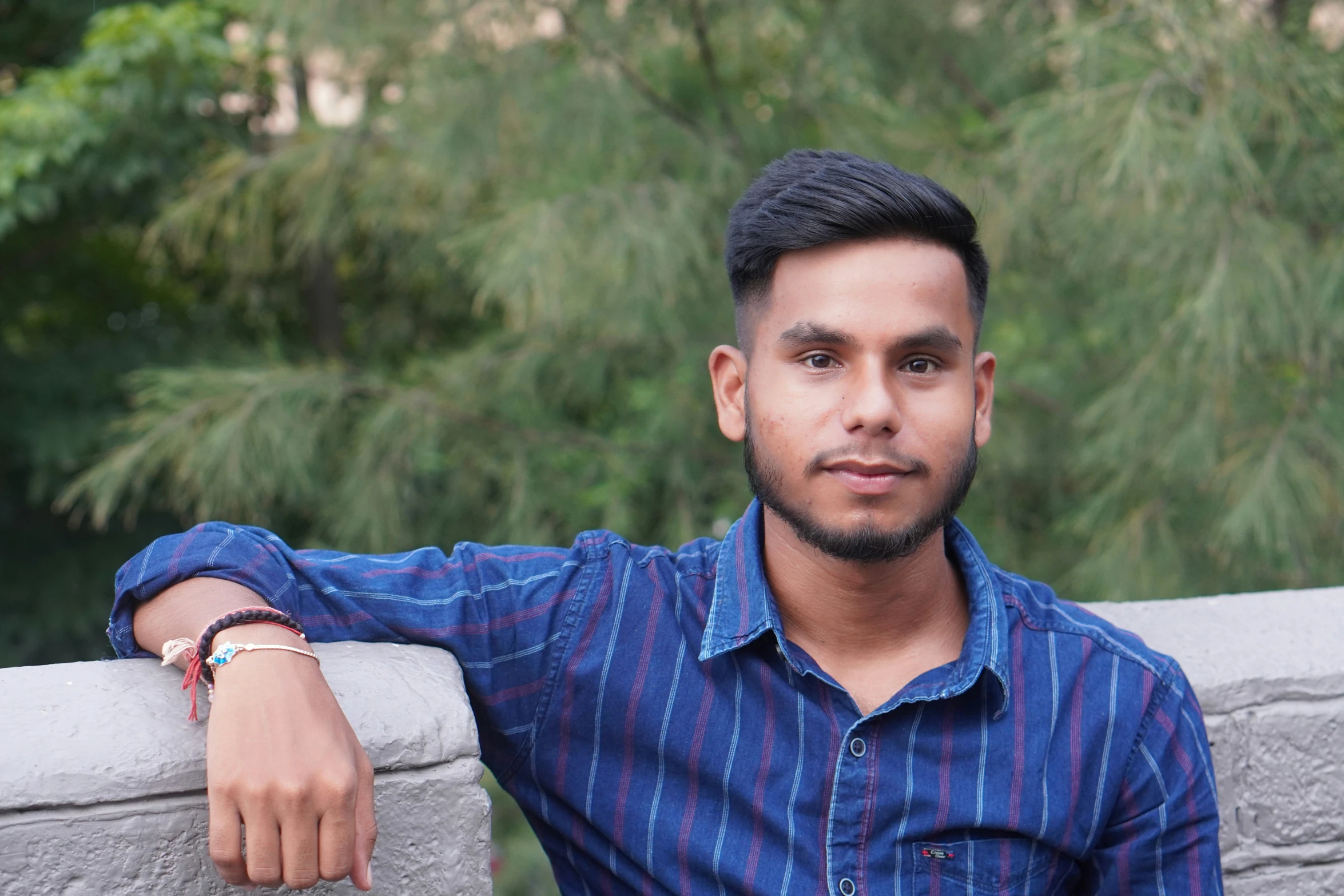 a man with his arm on the wall posing for a po