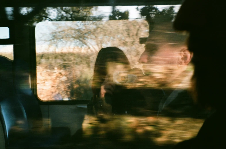 people sitting in a car with a reflection of a person holding an object