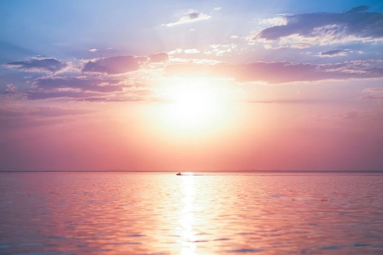 a lone boat in the distance as it sits in a body of water