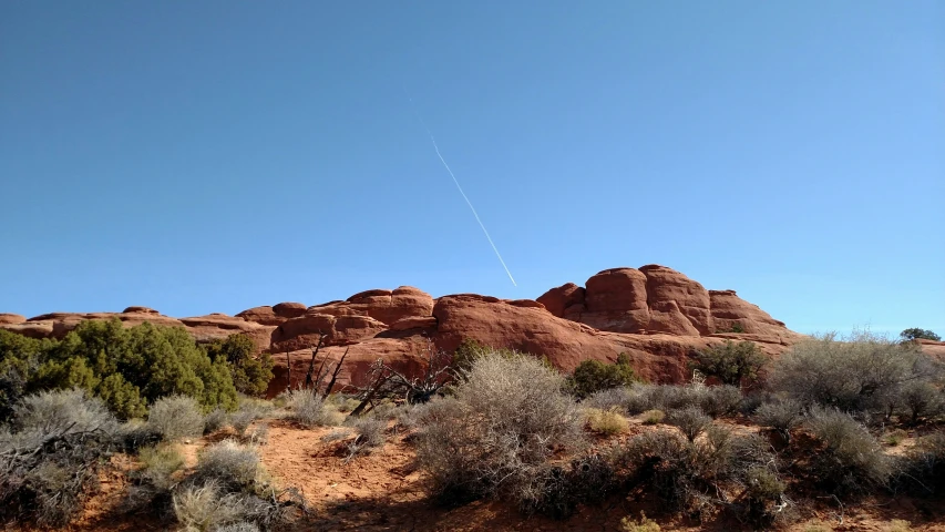 the airplane is flying in the blue sky near some rocks