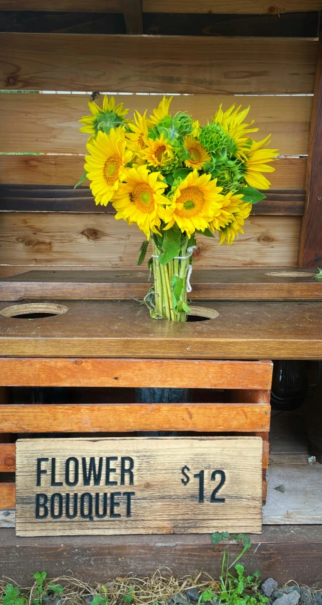 a wooden bench has flowers on it and a small wooden sign for flower bouquet