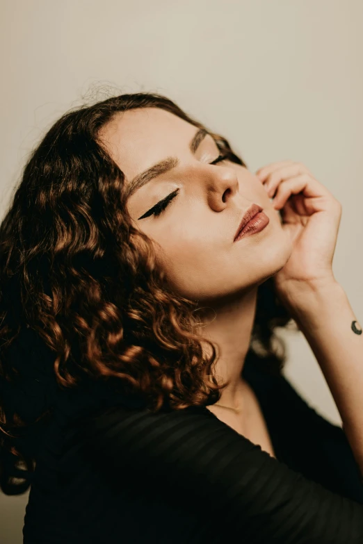 a woman with long curly hair posing for the camera