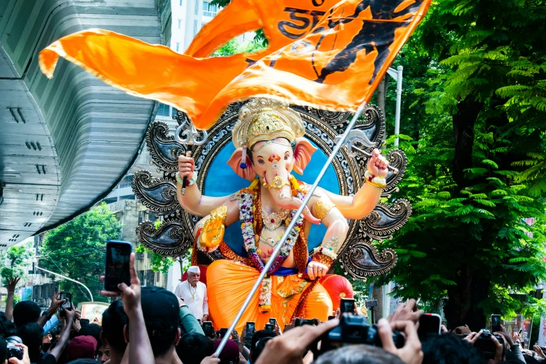 a crowd is gathered and taking pictures of an elephant with a flag