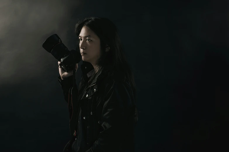 a girl holding a camera while standing on a black background