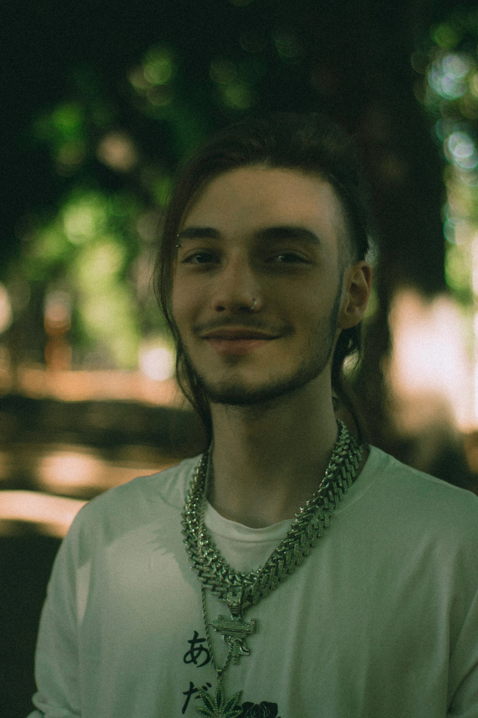 man standing in park wearing large necklaces on neck